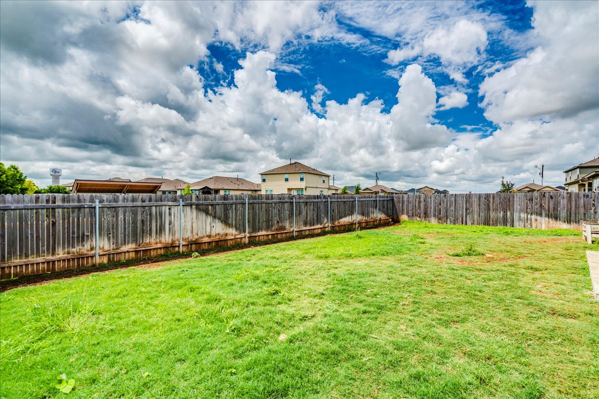 389 Salt Springs Road Kyle, TX 78640 - Photo 24 of 30 A spacious backyard awaits, fully fenced for privacy and outdoor enjoyment under an open sky.