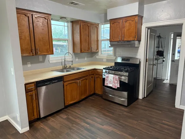 a kitchen with stainless steel appliances granite countertop a sink a stove and a wooden floors