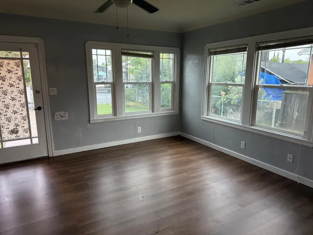 a view of an empty room with wooden floor and a window