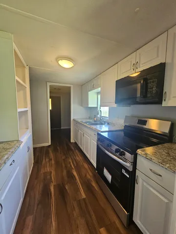 a kitchen with stainless steel appliances granite countertop a stove a sink and a microwave
