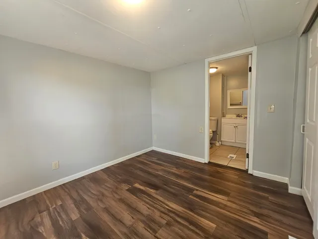 a view of an empty room with wooden floor and closet