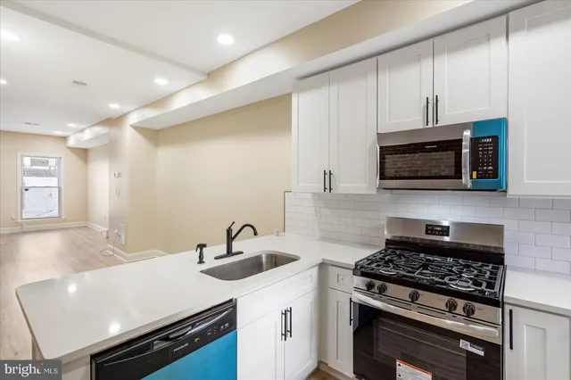 a kitchen with stainless steel appliances a sink a stove a microwave cabinets and a counter top space