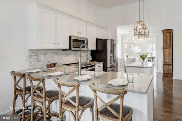 a kitchen with white cabinets stainless steel appliances and chandelier