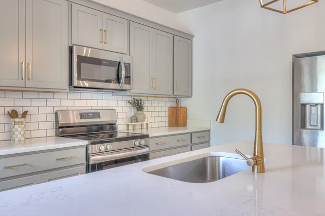 a kitchen with stainless steel appliances granite countertop a sink a stove and a microwave