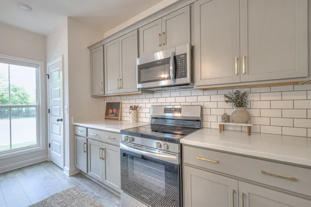 a kitchen with stainless steel appliances granite countertop white cabinets a stove a sink and dishwasher