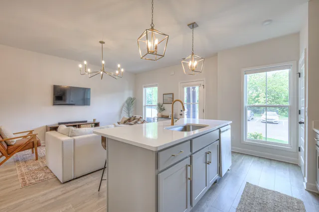 a kitchen with a sink dishwasher a dining table and chairs with wooden floor
