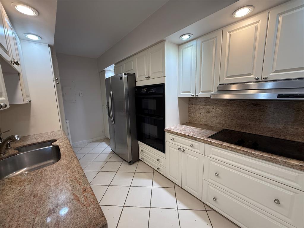 19707 Turnberry Way, Unit 7C Aventura, FL 33180 - Photo 6 of 40 a kitchen with granite countertop white cabinets and stainless steel appliances