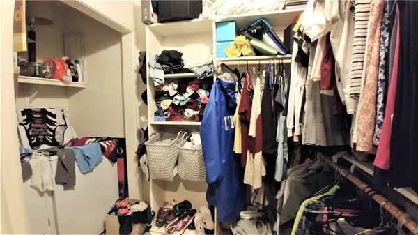 a view of walk in closet with clothes and shoes
