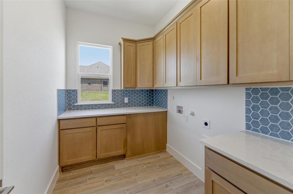 815 Vly Rdg Road Van Alstyne, TX 75495 - Photo 10 of 29 Utility room featuring light wood-finish cabinetry, white countertops, and a blue hexagonal tile backsplash