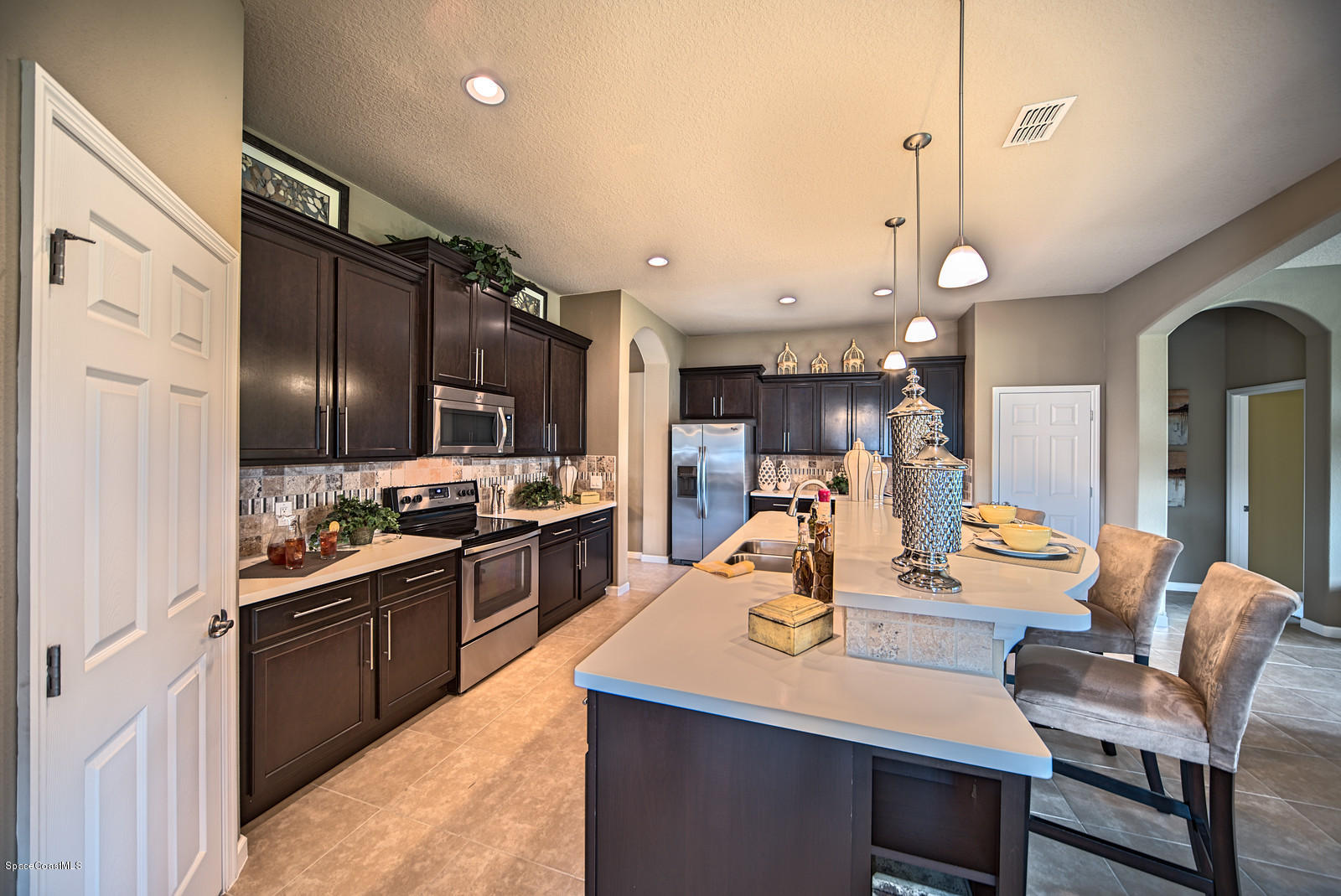 4052 Ruthann Circle Melbourne, FL 32934 - Photo 8 of 12 a kitchen with stainless steel appliances kitchen island granite countertop a table chairs in it and wooden floors