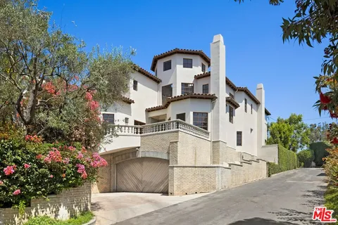 a view of a white house with large windows and a small yard