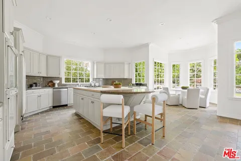 a kitchen with white cabinets and window
