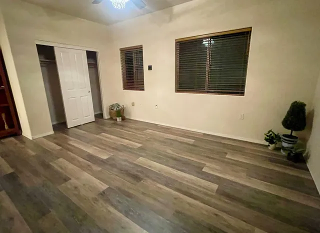 an empty room with wooden floor and windows