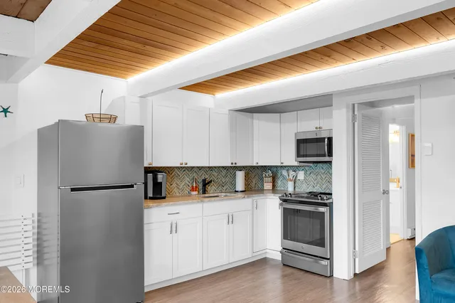 a kitchen with cabinets stainless steel appliances and wooden floor