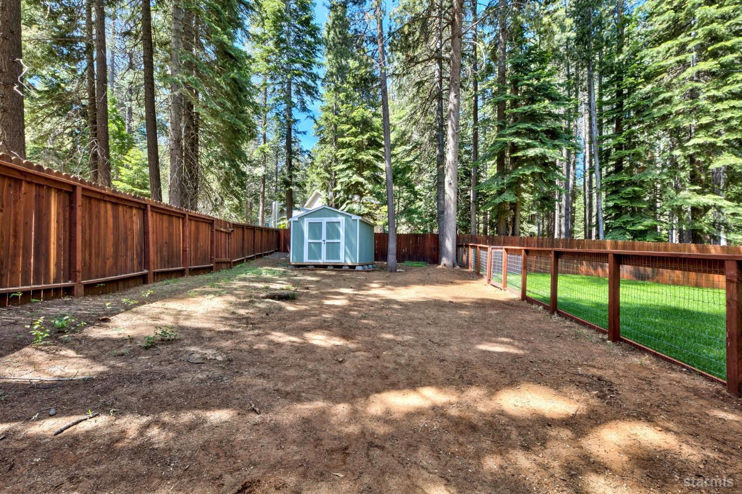 1569 Aztec Way South Lake Tahoe, CA 96150 - Photo 17 of 22 a view of a backyard with large trees and wooden fence