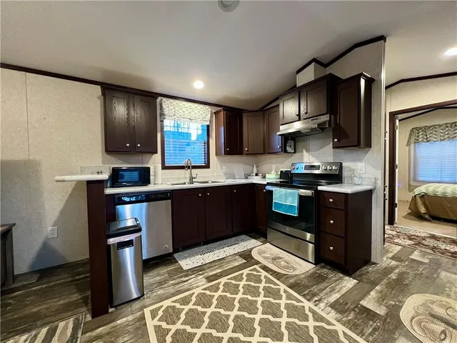 a kitchen with stainless steel appliances kitchen island granite countertop a refrigerator and a stove top oven