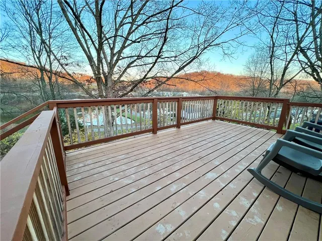 a view of balcony with wooden floor and fence and a large tree