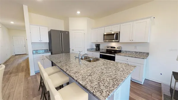 a kitchen with granite countertop a refrigerator stove top oven and sink