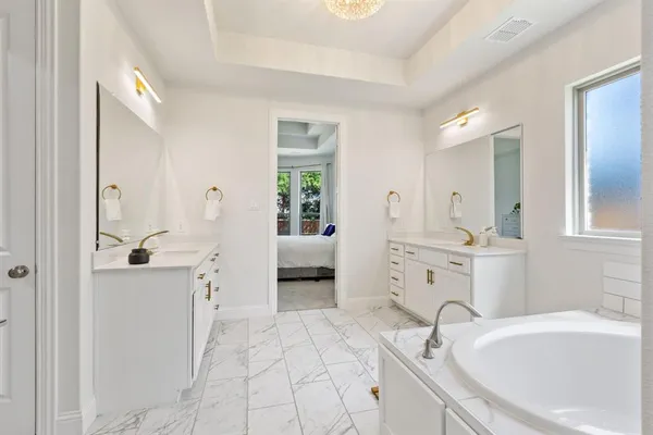 a spacious bathroom with a tub sink and mirror
