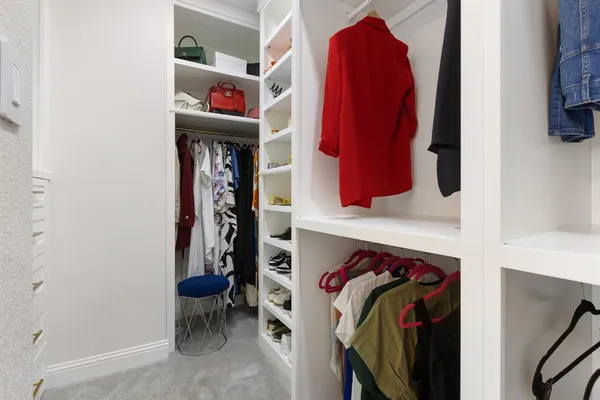 a view of walk in closet with clothes and shoes