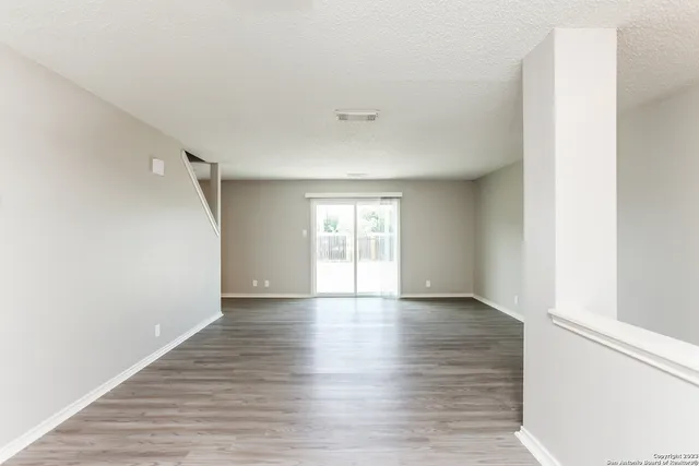 a view of an empty room with wooden floor and a window