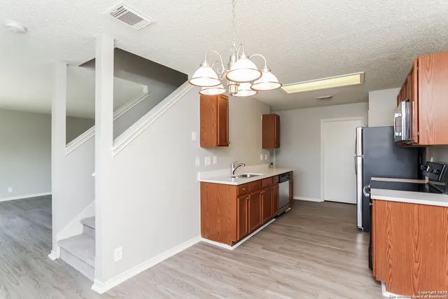 a kitchen with stainless steel appliances granite countertop a sink a stove top oven a counter space and wooden floor