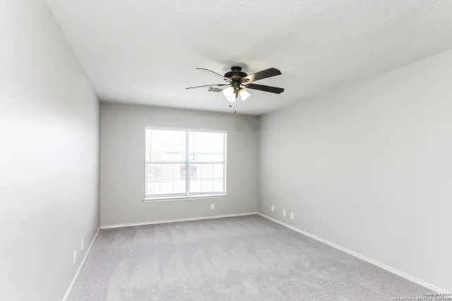 an empty room with a window and a fan