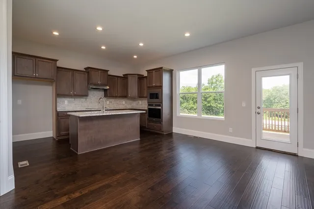 a kitchen with stainless steel appliances kitchen island wooden floors and wooden cabinets