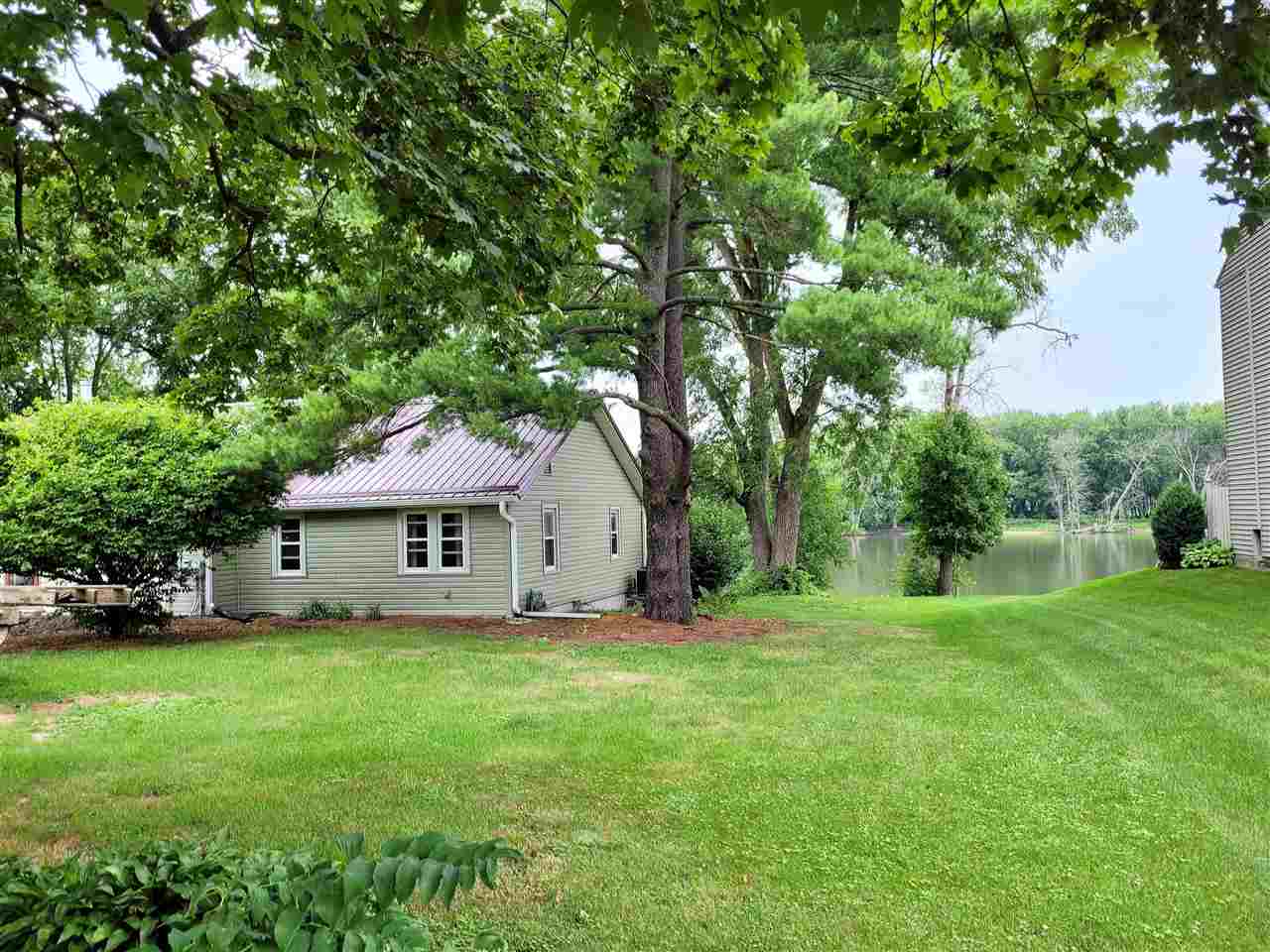 7504 North River Road Byron, IL 61010 - Photo 3 of 46 a yellow and red house with a big yard and large trees
