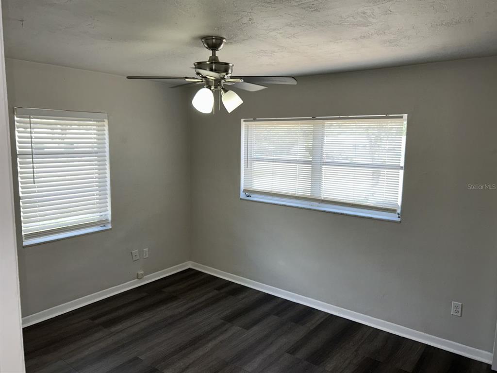1241 Pilgrim Road Spring Hill, FL 34606 - Photo 21 of 28 a view of an empty room with wooden floor and a window