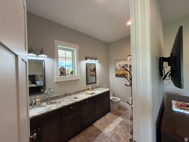 1325 South Round Road East Laketown, UT 84038 - Photo 15 of 40 Spacious bathroom featuring a double vanity with granite-style countertops, dark wood cabinetry, and a window for natural light