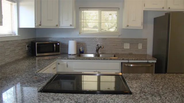 a kitchen with granite countertop a stove a sink and a microwave