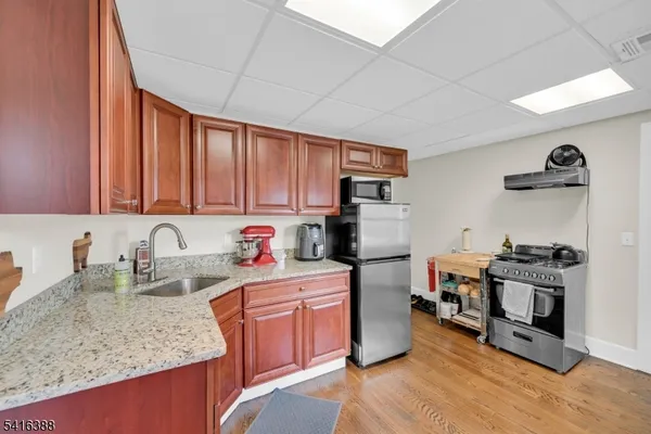 a kitchen with stainless steel appliances granite countertop a stove top oven a sink dishwasher and wooden cabinets with wooden floor