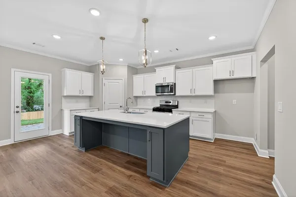 a kitchen with kitchen island granite countertop a sink cabinets and wooden floor