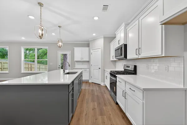a kitchen with stainless steel appliances granite countertop a sink a stove and a wooden floors