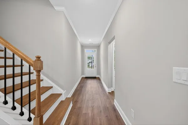 a view of a hallway with wooden floor and staircase