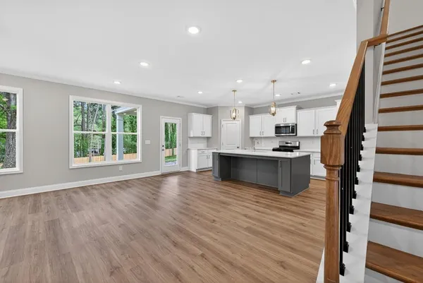 a large kitchen with stainless steel appliances granite countertop a large counter top a wooden floors and a large window