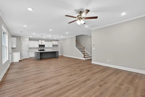 a view of an empty room with wooden floor and a ceiling fan