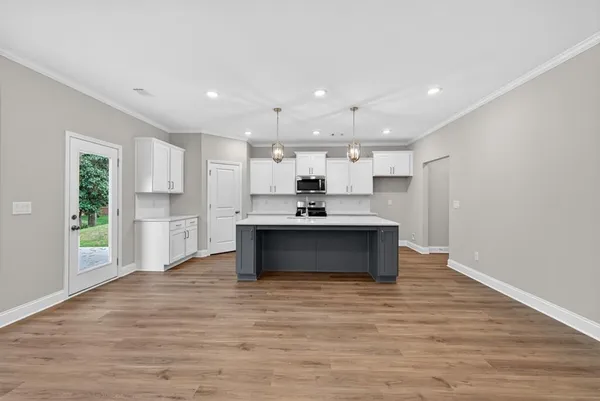 a view of kitchen with kitchen island a sink wooden floor and a refrigerator