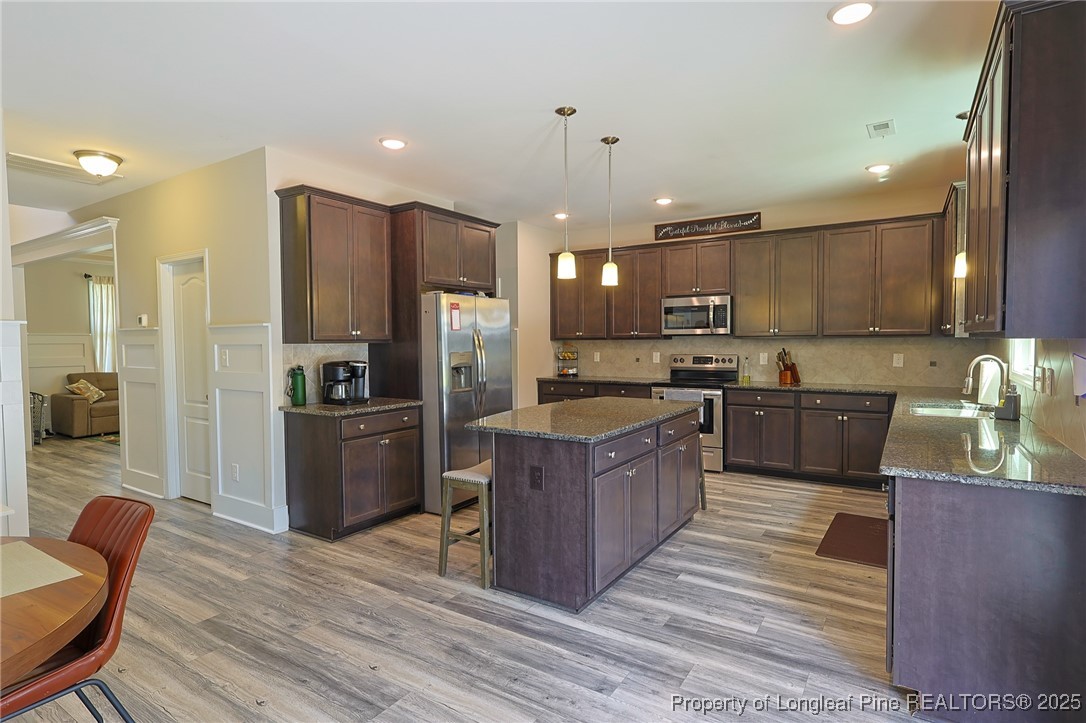 213 Sand Rock Road Fayetteville, NC 28306 - Photo 6 of 27 a kitchen with stainless steel appliances kitchen island granite countertop a refrigerator a stove a sink a dining table and chairs