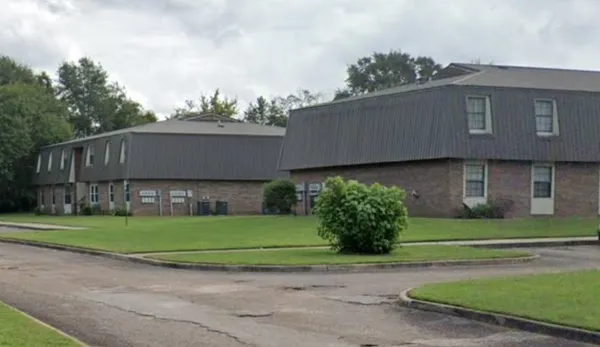 a front view of a house with a garden and trees