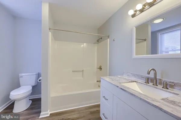 a bathroom with a granite countertop sink toilet a large mirror a bathtub and shower