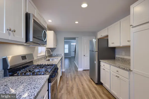 a kitchen with stainless steel appliances granite countertop a stove a sink and a microwave