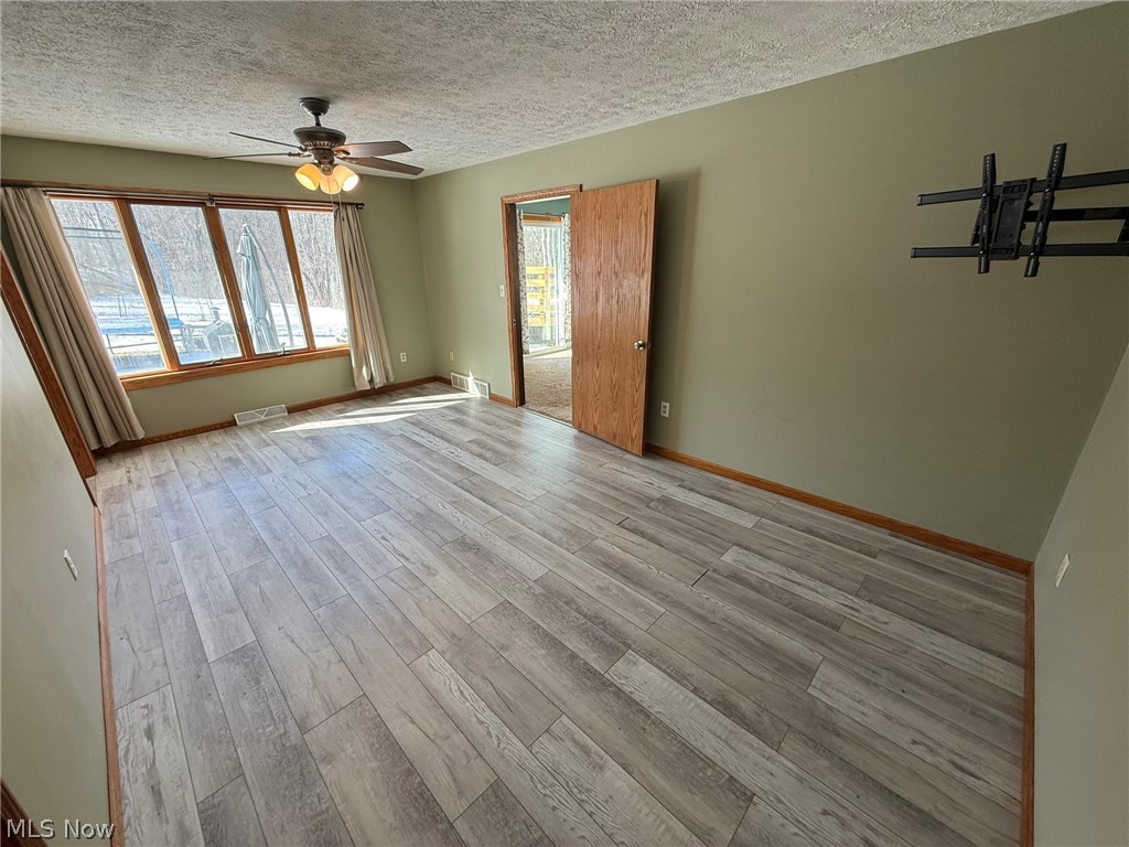6784 Old Zoarville Road Northeast Dover, OH 44622 - Photo 21 of 50 Empty room with light wood-type flooring, ceiling fan, and a textured ceiling