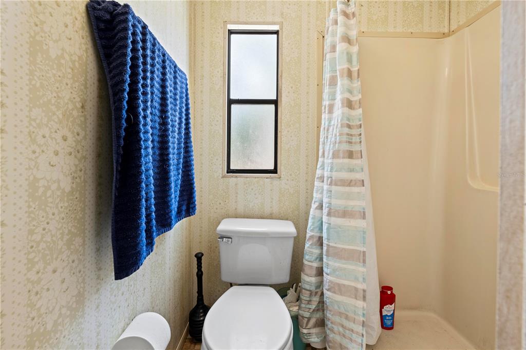 7373 Fall Street Brooksville, FL 34613 - Photo 15 of 26 a bathroom with a toilet and a shower curtain