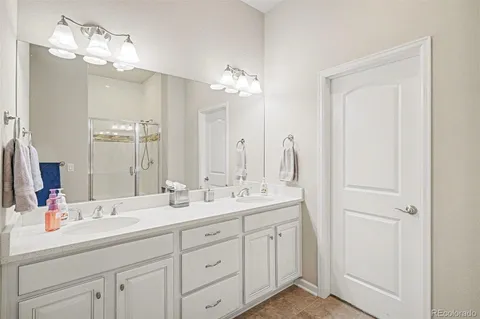 a bathroom with double vanity sinks a vanity a lamp and a mirror