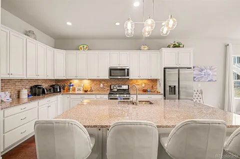 a kitchen with stainless steel appliances granite countertop a sink refrigerator and cabinets