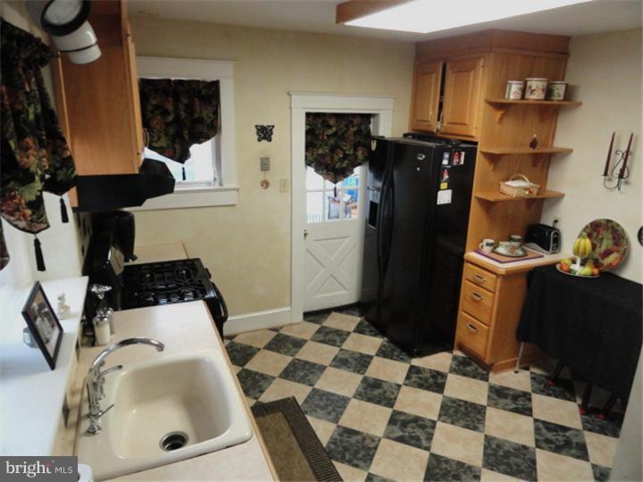 47 North Rolling Road Springfield, PA 19064 - Photo 6 of 16 a room with a black white checkered floor with a sink and a refrigerator