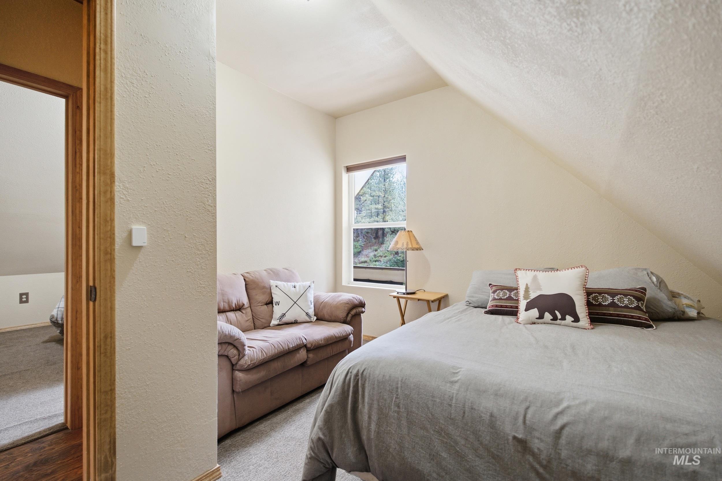 3980 North Pine-Featherville Road Mountain Home, ID 83647 - Photo 24 of 35 Carpeted room featuring a sloped ceiling, a window with outdoor scenery, and a wooden doorframe