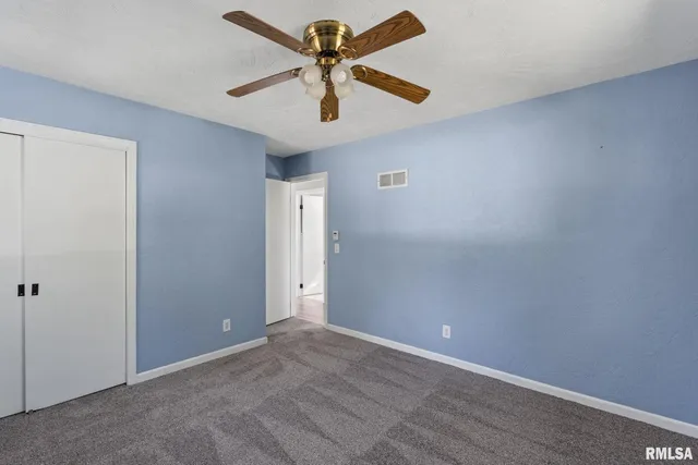 an empty room with closet and a chandelier fan